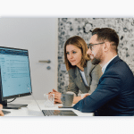 Two colleagues look at a desktop.