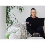 A man sits on a couch and works at his laptop.