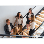 A group of people stand in a stairway having a chat.