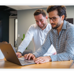 Two colleagues look at a laptop